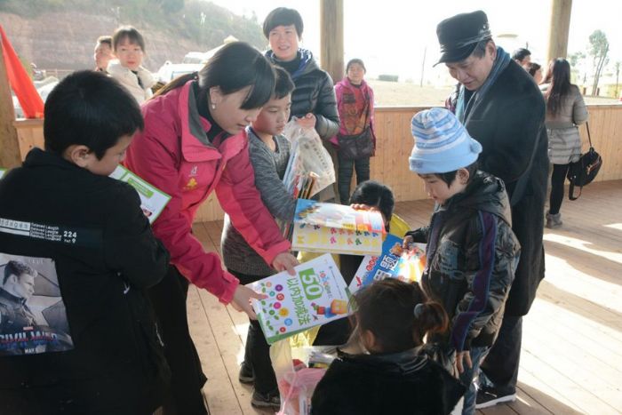 ▲志愿者将新年礼物送给孩子们。记者田茂培摄
