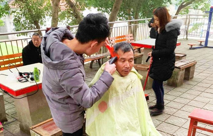 志愿者为老大爷理发。全媒体记者米莲摄
