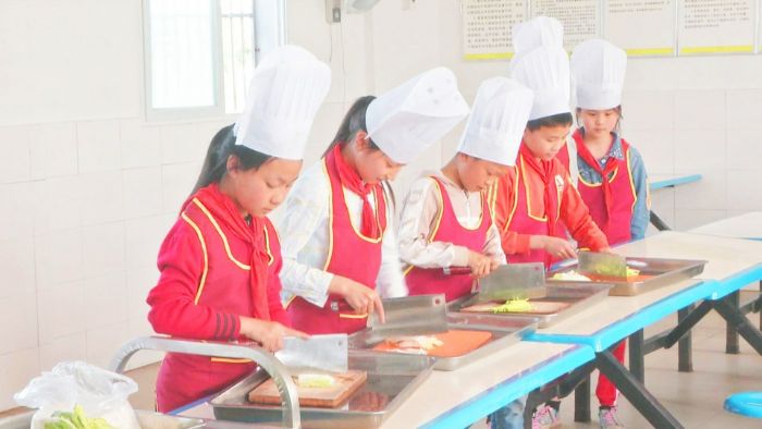 新华小学烹饪兴趣班学生练习切菜。
