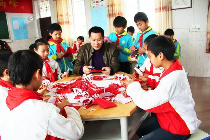 　　④长兴小学校长王树涛教孩子们剪纸。

