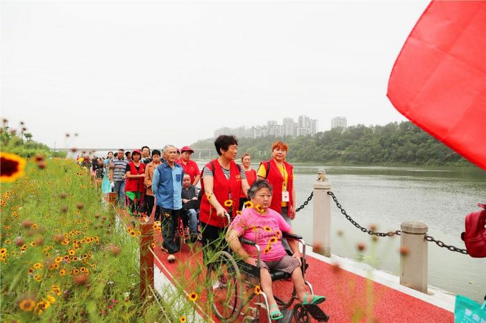 志愿者陪残疾人朋友逛滨江公园。
