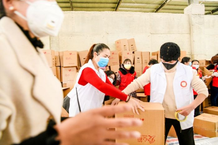 志愿者对采摘的果蔬打包装箱。
