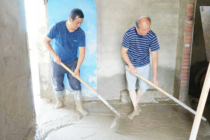姜虎（左）帮助居民清淤。
