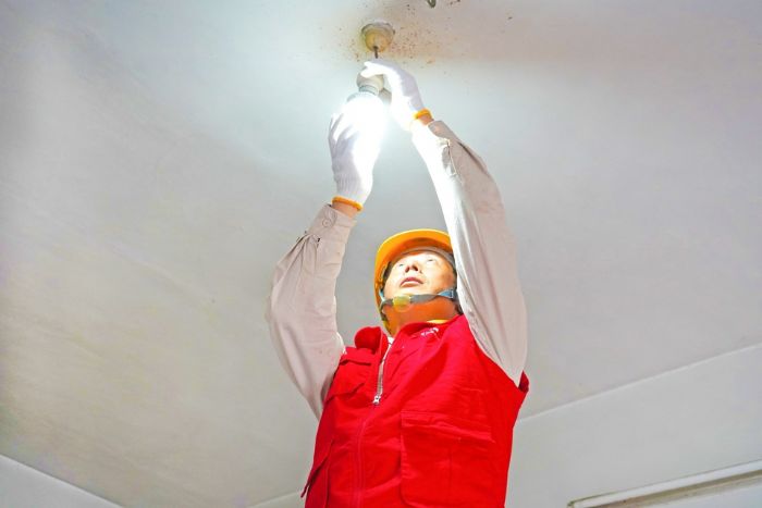 　　电力工人为贫困户修理电器。
