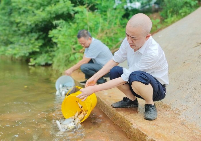工作人员在琼江边增放鱼苗。
