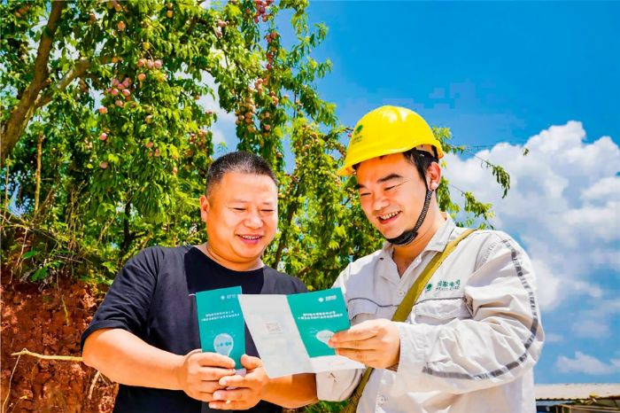 工人向果农宣传安全用电知识。
