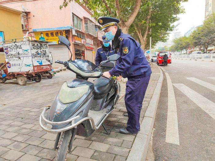 城管人员维护城市车辆乱停乱放。
