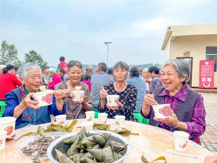 区慈善会邀请老人们品尝美味的粽子。
