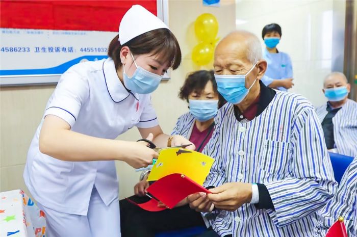  在区人民医院住院部，护士与老年患者一起制作小红旗，共庆国庆、重阳双节。